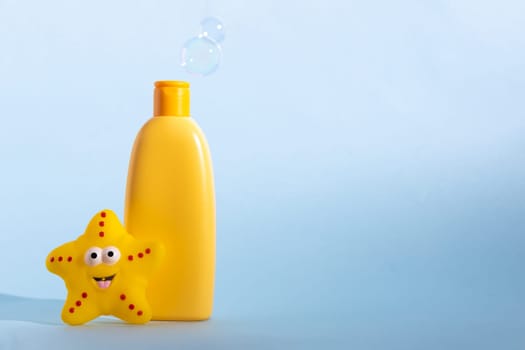 Mockup bottle of baby washing gel, bath foam, liquid soap or shampoo with yellow star fish and flying soap bubbles. Children's hygiene. Template for design