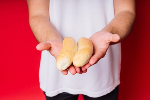 Man with freshly baked bread in hands isolated on red background studio