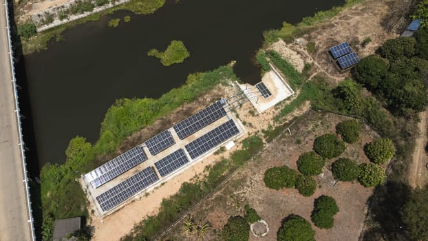 Top view on photovoltaic solar power panels. Drone aerial view of solar panels with water pumps, agricultural equipment for irrigation near rivers from clean energy or solar energy. Alternative electricity source.