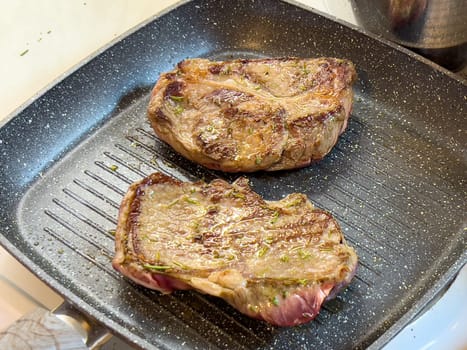 Juicy steaks with a crispy crust are fried in a grill pan on the stove. High quality photo