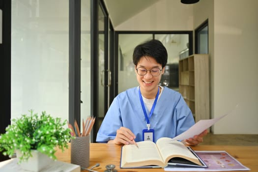 Medical student reading books, preparing for university exams in library. Medical internship concept.