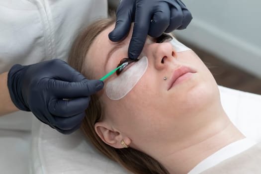 Beautician Applies Lash Lift Lotion On Rolled Hair During Eyelash Lamination Treatment Procedure In Beauty Salon. Curling, Staining, Extension Procedures For Lashes. Horizontal Plane. Step By Step,