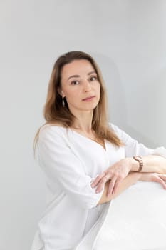 Portrait of Charming Beautician in White Lab Coat Looking at Camera With Smile, Near Couch, Looking at Camera in Spa Salon. Vertical Plane High quality photo