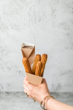 Woman taking churros from a cone and dipping it in chocolate sauce