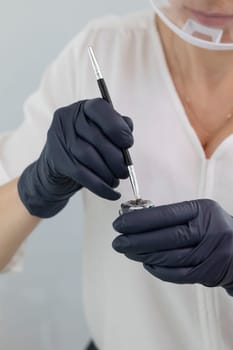 Cropped Beautician Prepares Tint for Dying Lashes During Eyelash Lamination Treatment Procedure In Beauty Salon. Curling, Staining, Extension Procedures For Lashes. vertical plane. High quality photo