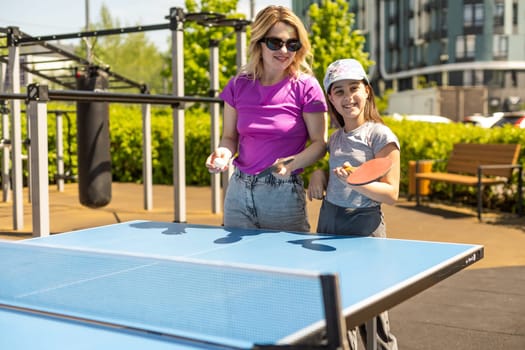 Happy Mother and Daughter Learning to Play Ping Pong Sport Cheerful family playing leisure sports enjoying table tennis.