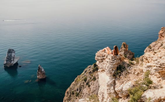 Woman travel sea. Happy tourist taking picture outdoors for memories. Woman traveler looks at the edge of the cliff on the sea bay of mountains, sharing travel adventure journey.