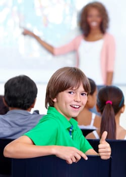 Thumbs up, teaching and child portrait for happy learning, support and thank you with education success, school or geography. Like, yes and achievement hand or emoji of boy kid with map in classroom.