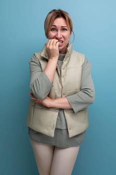 portrait of a worried European 30 year old woman in comfortable clothes biting her nails.