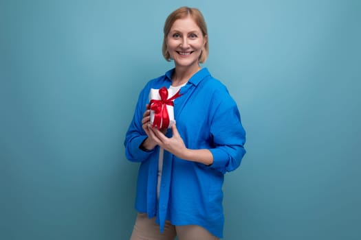 cute middle aged woman received birthday present on blue background copy space.