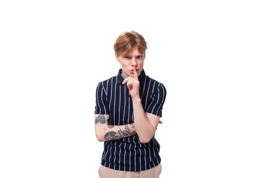 smart 25 year old blond man with tattoos in a striped polo thinking.