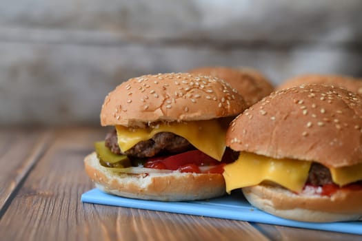 Several homemade burgers on a plastic cutting board and wooden background