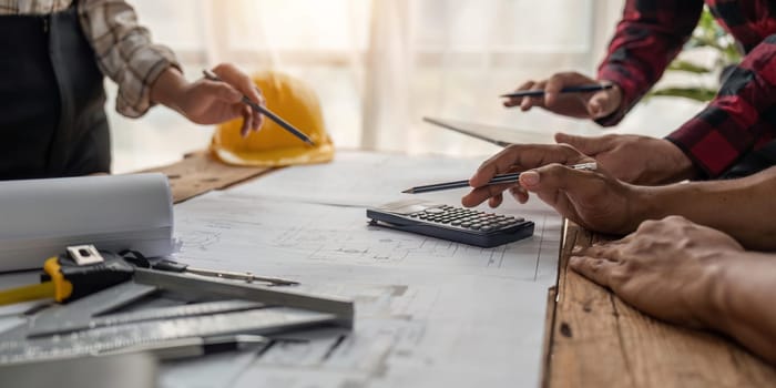 team engineer checks construction blueprints on new project with engineering tools at desk in office.