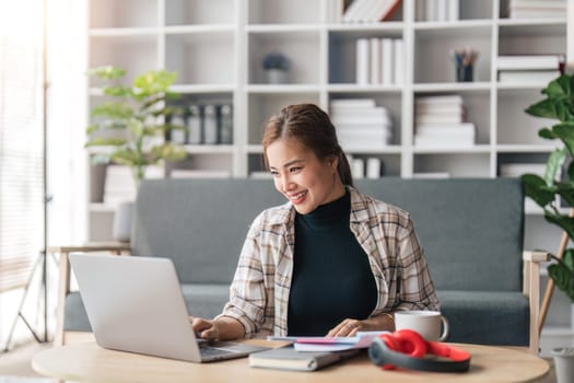 Image of pleased happy cheerful cute beautiful business woman sit in home using laptop computer listening music with earphones.