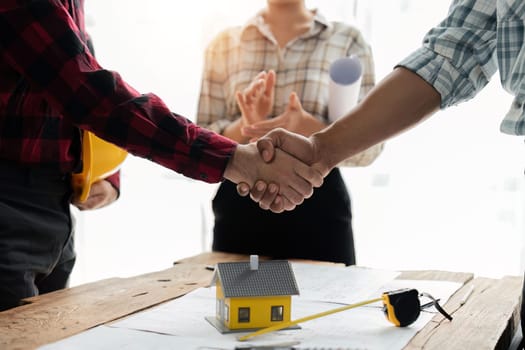 Close up view of engineering team shaking hands after the deal is completed. Team planning for architecture project.