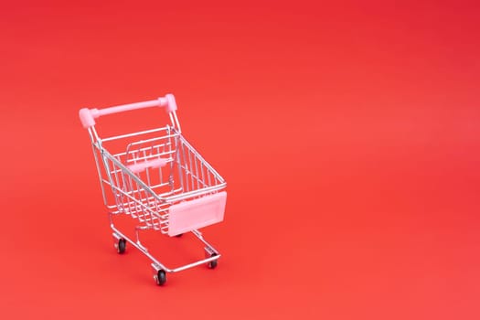 Mini shopping trolley for shopping on red background, consumer concept,