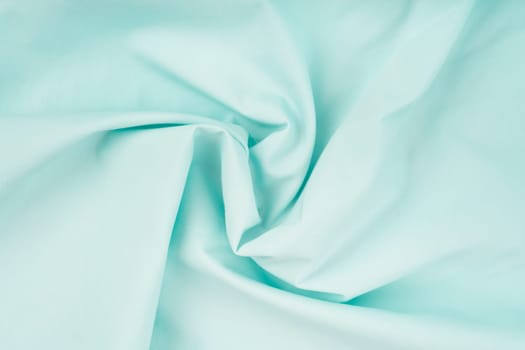 Delicate background of light blue soft plush fleece with embossed folds and waves. A modern backdrop for decorating and designing textiles.