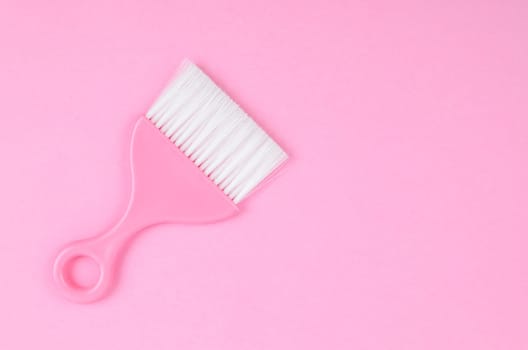 Pink cleaning brush on pink background.