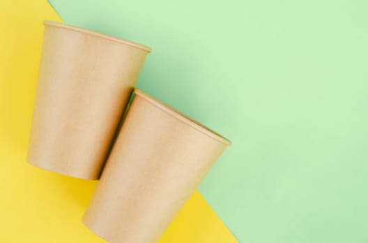 Brown paper disposable eco-friendly cups on green background.