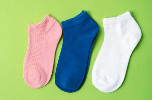 Socks of different colors on green color background.