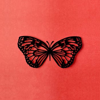 Black color paper butterfly carve on a red background.