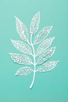 Carve of white paper leaves on a light green cardboard background.