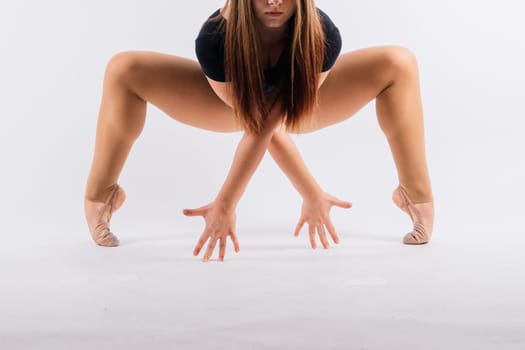 Flexible girl, rhythmic gymnastic artist jumping on white dark background. Grace in motion, action.