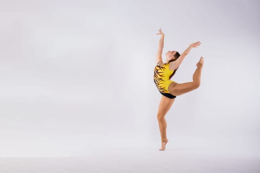 Flexible girl, rhythmic gymnastic artist jumping on white dark background. Grace in motion, action.