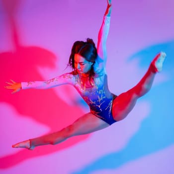 Flexible girl, rhythmic gymnastic artist jumping on white dark background. Grace in motion, action.