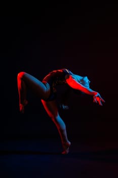 Flexible girl, rhythmic gymnastic artist jumping on white dark background. Grace in motion, action.