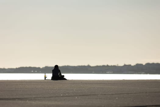 A lonely man drinking wine at the waterfront. Mid shot