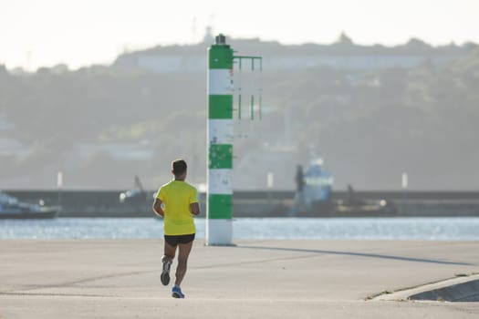 Man in sportswear jogging at the waterfront. Mid shot