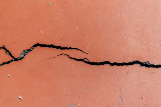 Crack in red-painted asphalt on a sports field.