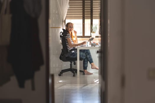 Smiling woman freelancer working at the kitchen table - looking in the camera. Mid shot