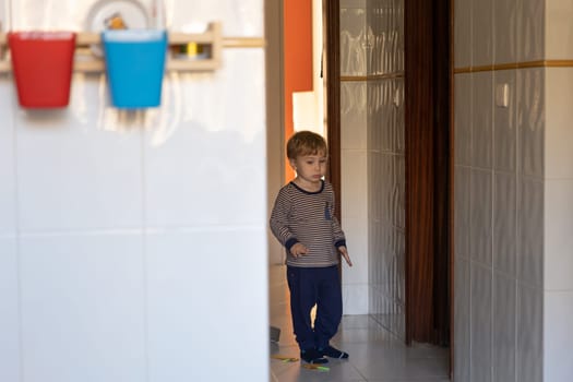 A little boy stands in the corridor in the apartment. Mid shot