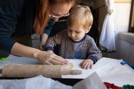 A woman with her little son making cookies. Mid shot