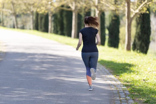 Adult woman jogging in the park. Mid shot