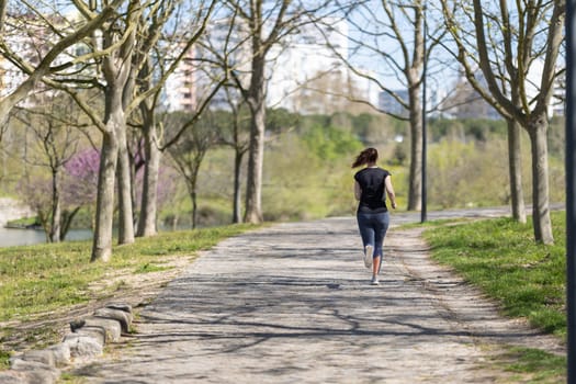 Adult woman jogging in the park - back view. Mid shot