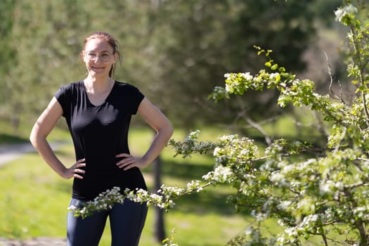 Adult smiling woman in sports clothes on nature. Mid shot