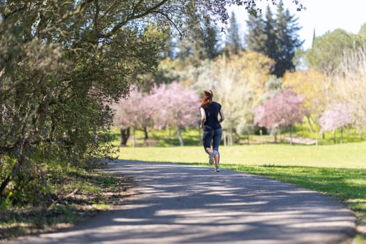 An adult woman in leggings jogging on nature. Mid shot