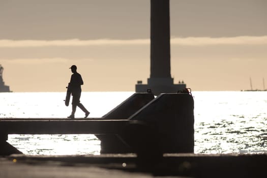 Skateboarders hang out on the waterfront at early sunset. Mid shot