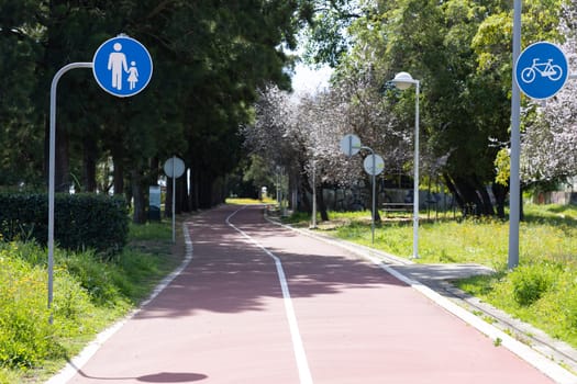 A path in the park - signs indicating the path for a bicycle and a parent with a child. Mid shot