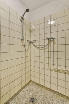 a shower stall in a tiled bathroom with black and white tiles on the walls, along with a metal hand rail