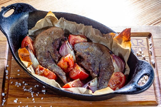 Beef tongue baked in a cast-iron pan with vegetables.