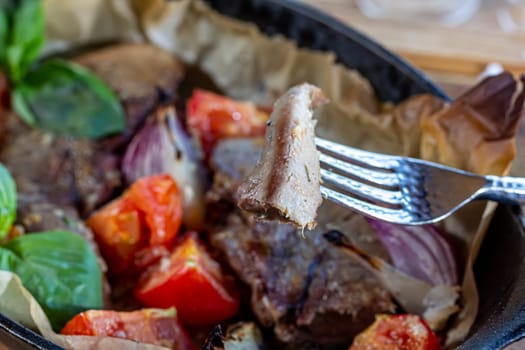 Beef tongue baked in a cast-iron pan with vegetables.