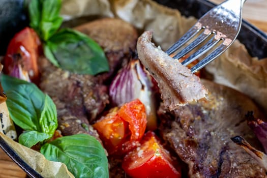 Beef tongue baked in a cast-iron pan with vegetables.