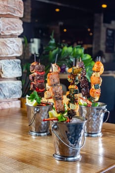 A lot of mini-kebabs of meat, fish, chicken, shrimp, vegetables on wooden skewers.