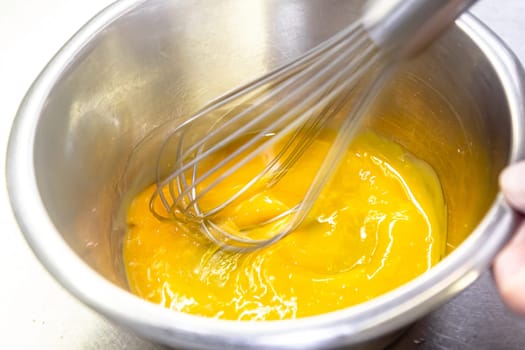 The cook whips the egg sauce with a whisk