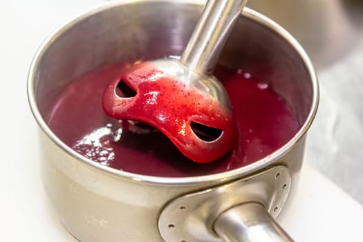 The cook uses a blender to prepare berry puree