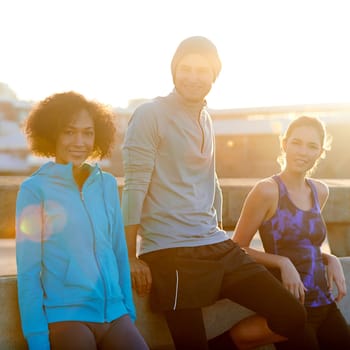 Just a quick breather. Portrait of three friends taking a break at the road side during a morning jog